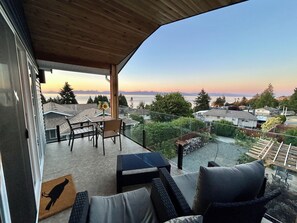 Ein Balkon mit Blick auf Stadt und Berge, ausgestattet mit Tisch, Stühlen und einer Couch.