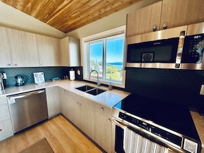 Una cocina moderna con electrodomésticos de acero inoxidable, armarios de madera y un amplio ventanal con vistas al exterior.