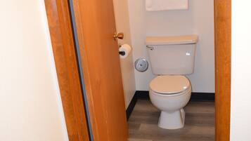 Ein Badezimmer mit Holztür, Toilette und Handtuchhalter mit Handtüchern.