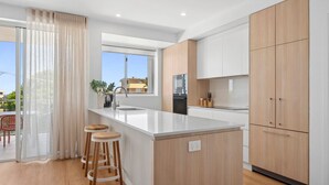 Una cocina moderna con una isla central, armarios de madera y un amplio ventanal con vistas al exterior.