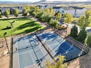 An outdoor tennis court surrounded by trees and residential buildings. - Zion's Sunset is BRAND NEW!!! Beautiful courtyard, fun game room, roof top deck (Hurricane)