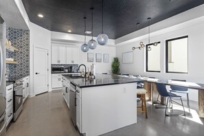 A modern kitchen with white cabinets, a black countertop, and pendant lighting. - Zion's Sunset is BRAND NEW!!! Beautiful courtyard, fun game room, roof top deck (Hurricane)