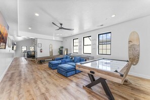 A spacious room with a pool table, blue seating, and large windows. - Zion's Sunset is BRAND NEW!!! Beautiful courtyard, fun game room, roof top deck (Hurricane)