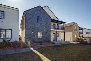 A modern residential building with a stone facade, a balcony, and a well-maintained lawn. - Zion's Sunset is BRAND NEW!!! Beautiful courtyard, fun game room, roof top deck (Hurricane)