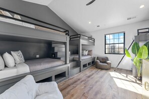 A modern, multi-level bunk bed room with a large window, a plant, and a wooden floor. - Zion's Sunset is BRAND NEW!!! Beautiful courtyard, fun game room, roof top deck (Hurricane)