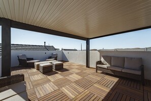 A covered outdoor seating area with wicker furniture and a wooden floor. - Zion's Sunset is BRAND NEW!!! Beautiful courtyard, fun game room, roof top deck (Hurricane)