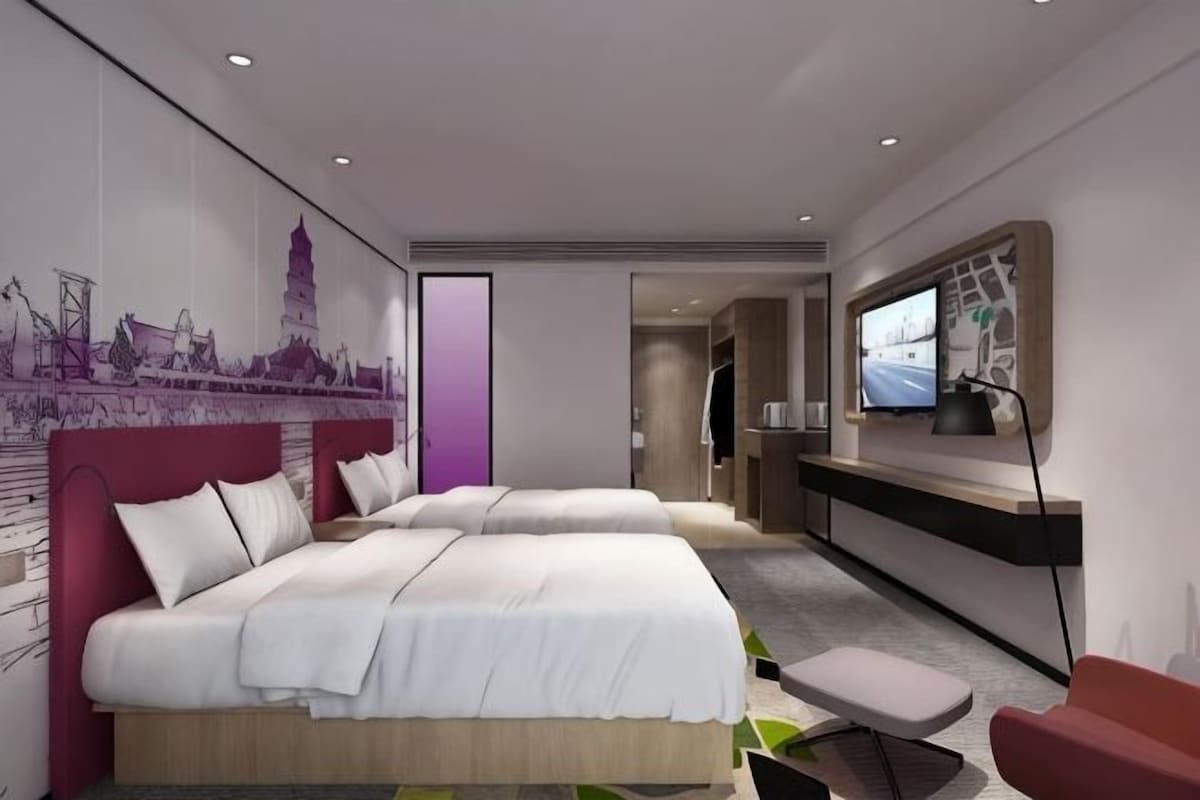 Habitació d'hotel moderna amb dos llits, una taula de treball i una televisió.