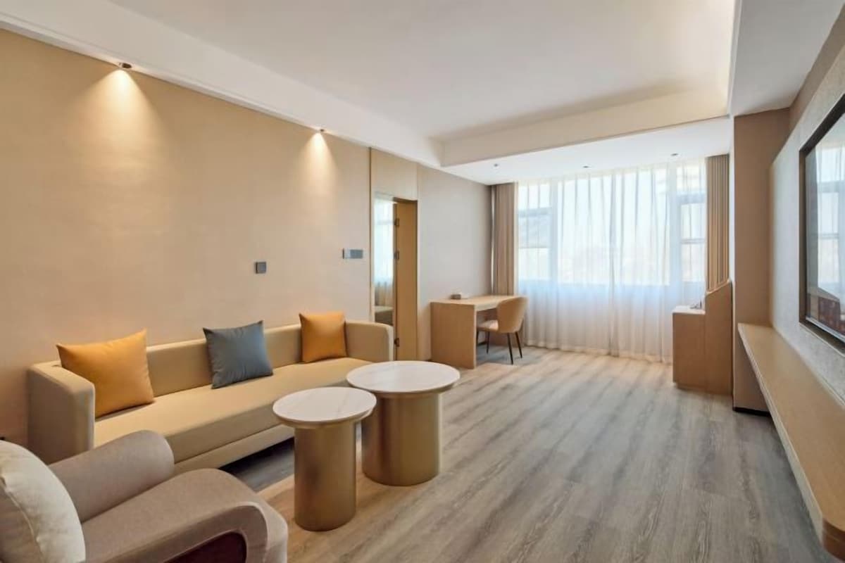 Habitació d'hotel moderna amb un sofà, dues taules rodones i una zona de menjador.