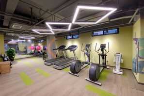 Un gimnasio con cintas de correr, elípticas y pelotas de ejercicio.