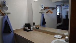 Een badkamer met een wastafel, spiegel en een kledingroede.