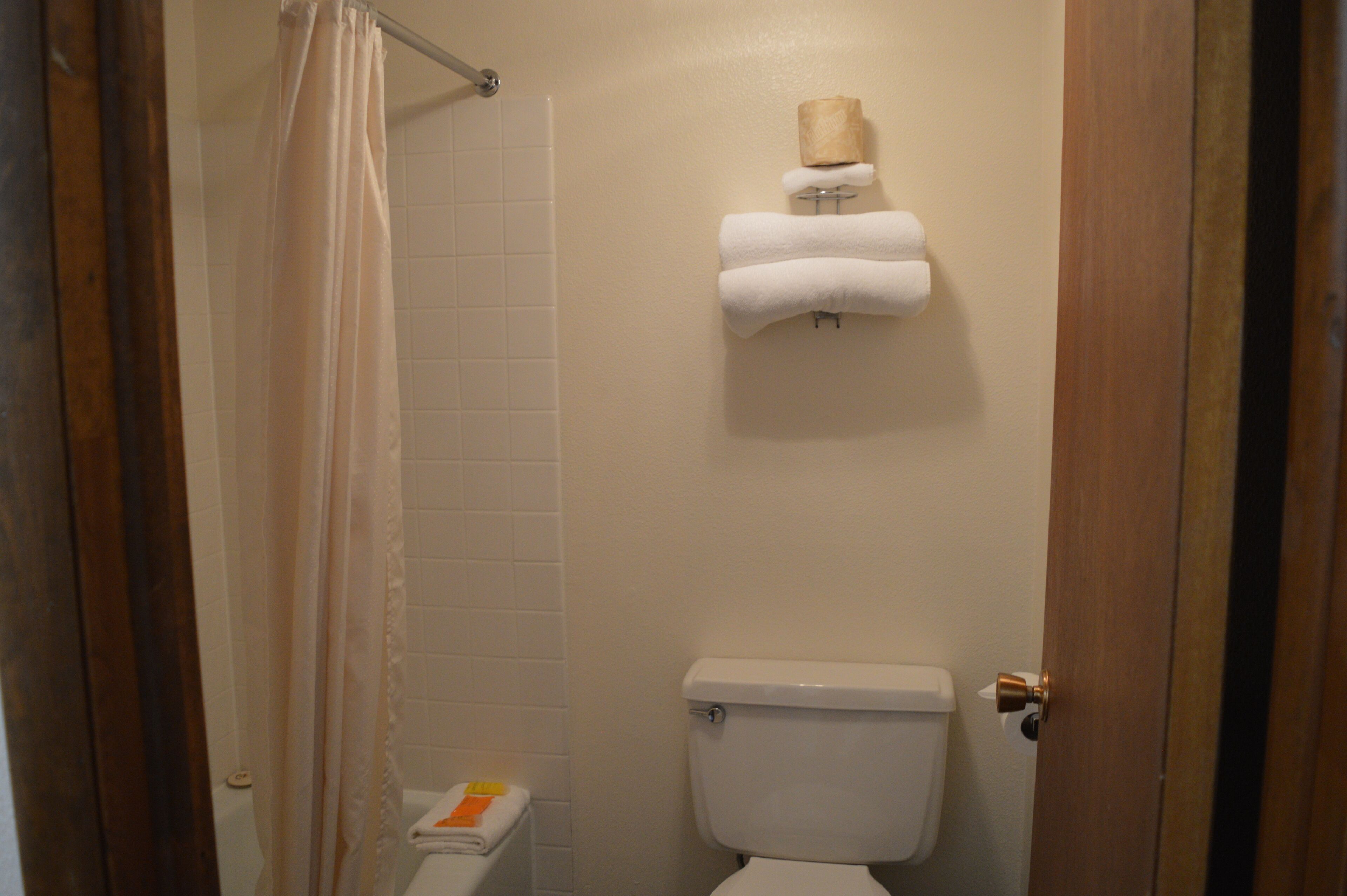 Une salle de bain équipée de toilettes, d’un rideau de douche et d’un porte-serviettes avec des serviettes.