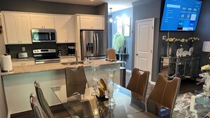 A modern kitchen with white cabinets, stainless steel appliances, and a glass dining table with chairs. - Meadowstone Luxe Stay - 5star Comfort  (Atlanta)