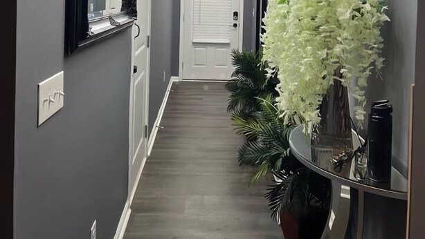 A hallway with a modern chandelier, a mirror, a door, and a decorative white flower arrangement. - Meadowstone Luxe Stay - 5star Comfort  (Atlanta)