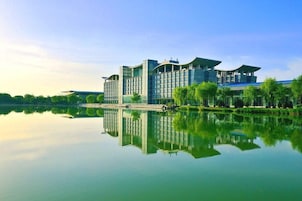 Un hotel moderno reflejado en el agua, rodeado de vegetación.