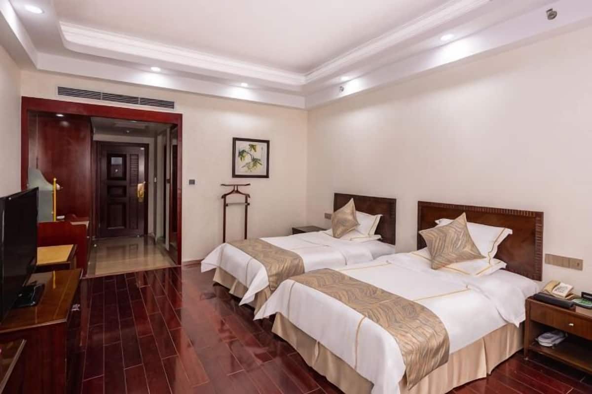 A hotel room with two beds, a TV, a desk, and a nightstand.