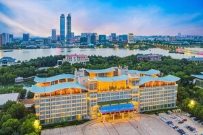 A hotel with a parking lot, a river in the background, and a city skyline. - Yue Hai Hotel (Yinchuan)