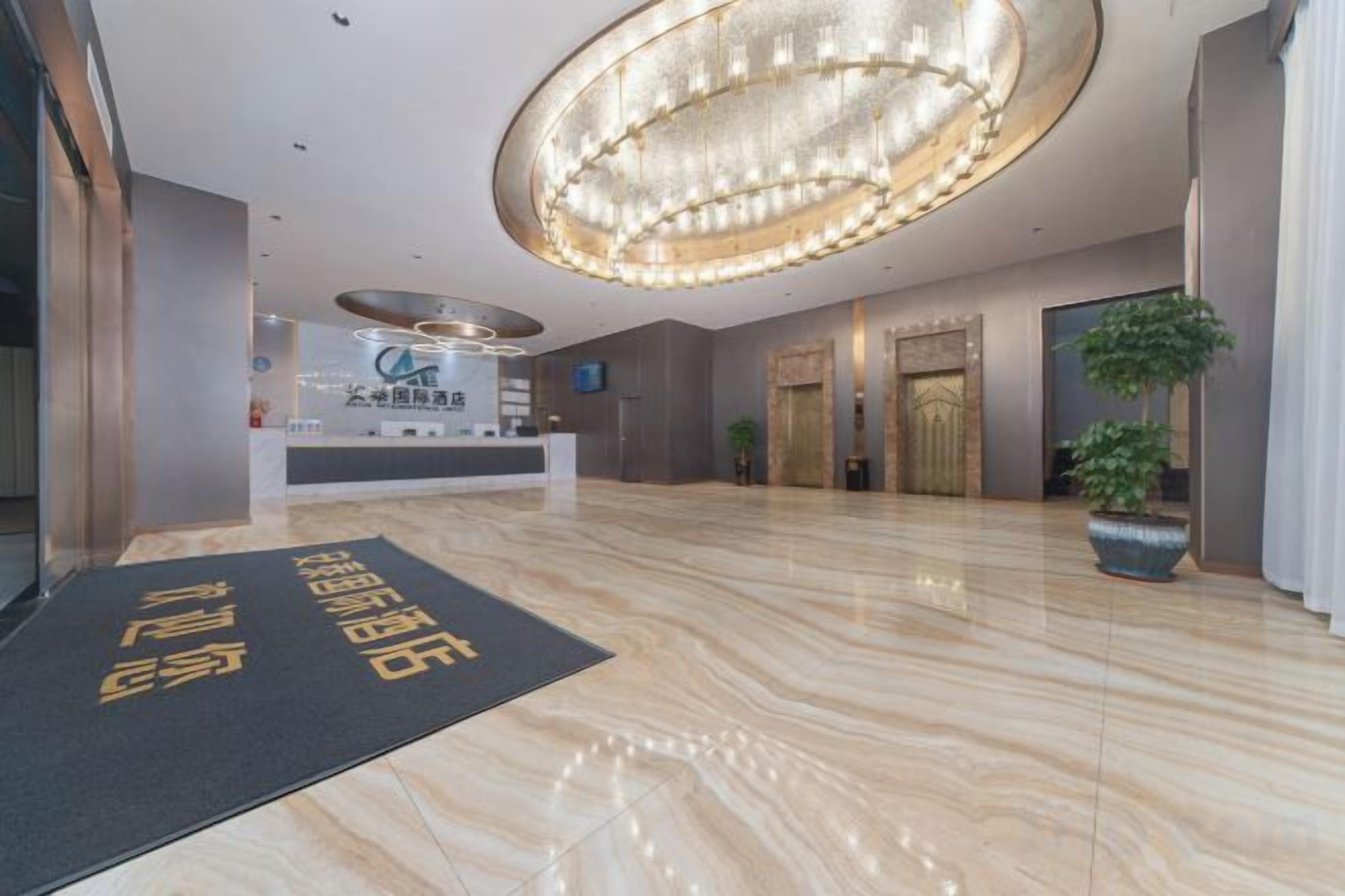 Un vestíbulo de hotel con una recepción, un gran candelabro y un área de espera.