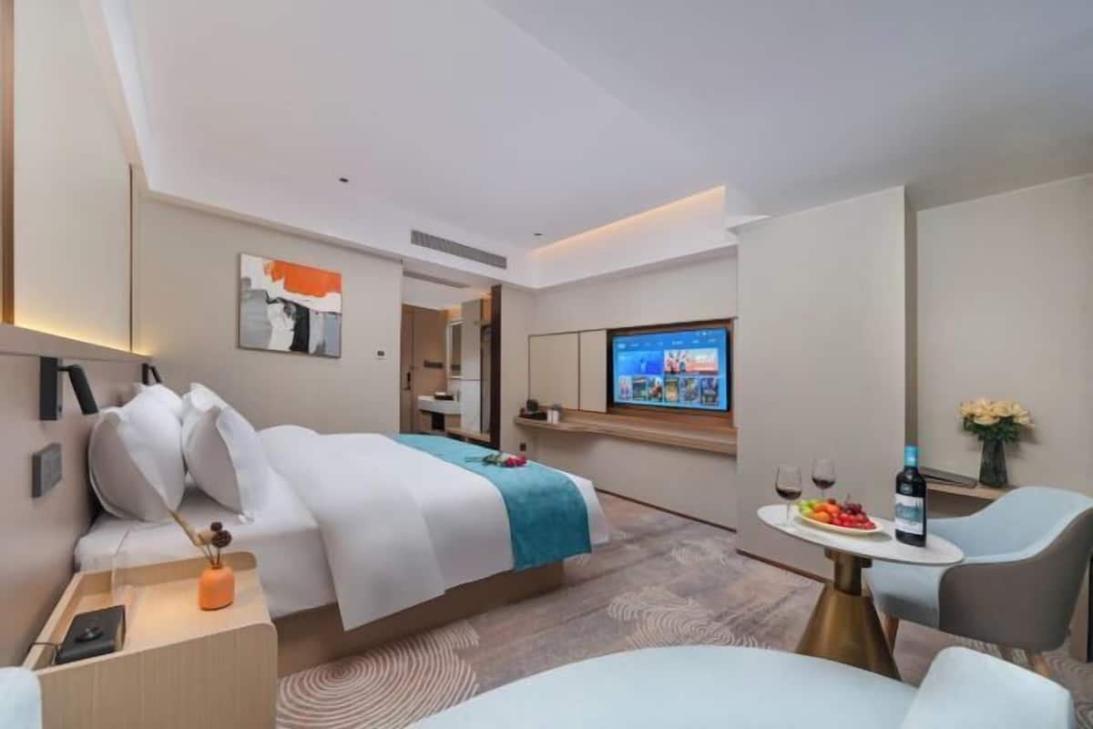 Une chambre d’hôtel moderne équipée d’un lit, d’un bureau, d’une télévision et d’un coin repas avec une table et des chaises.