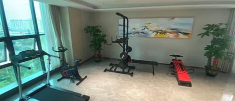 Una habitación con caminadora, bicicletas estáticas y equipo de ejercicio.