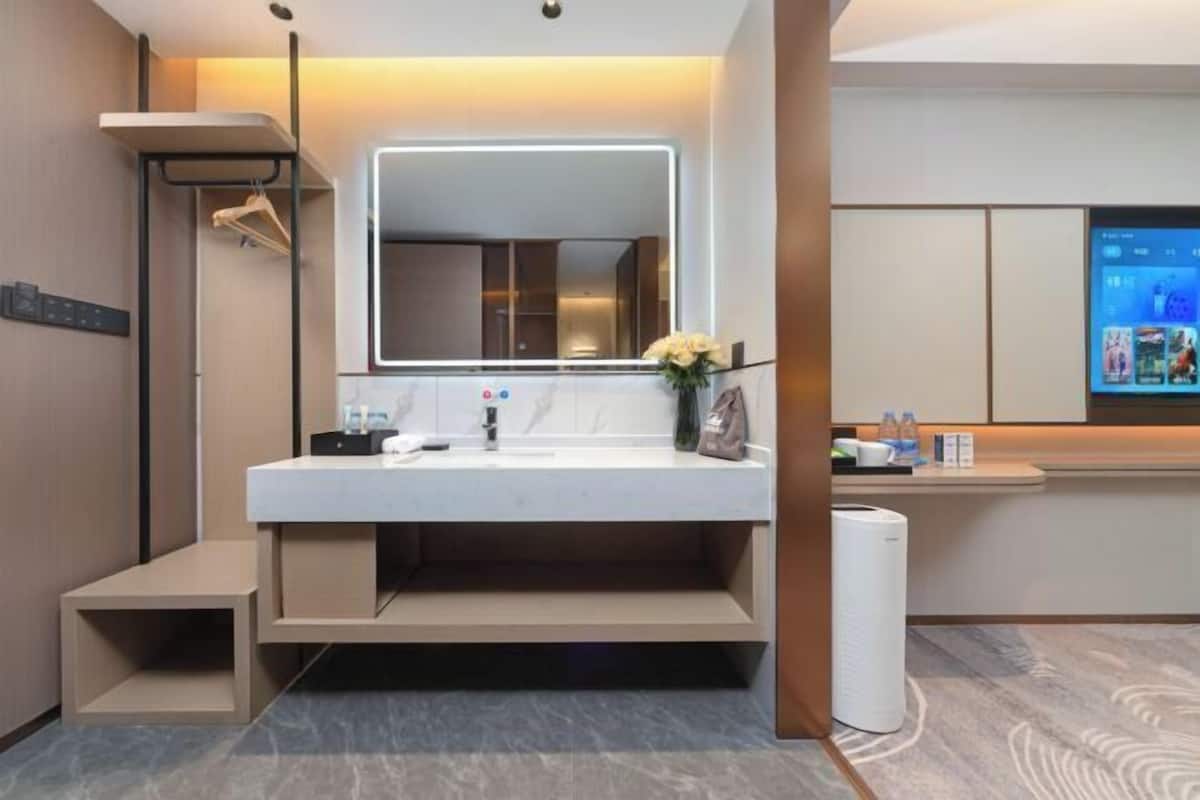 Une salle de bain moderne avec un grand miroir, un lavabo, un porte-serviettes et un petit marchepied pour faciliter l’accès.