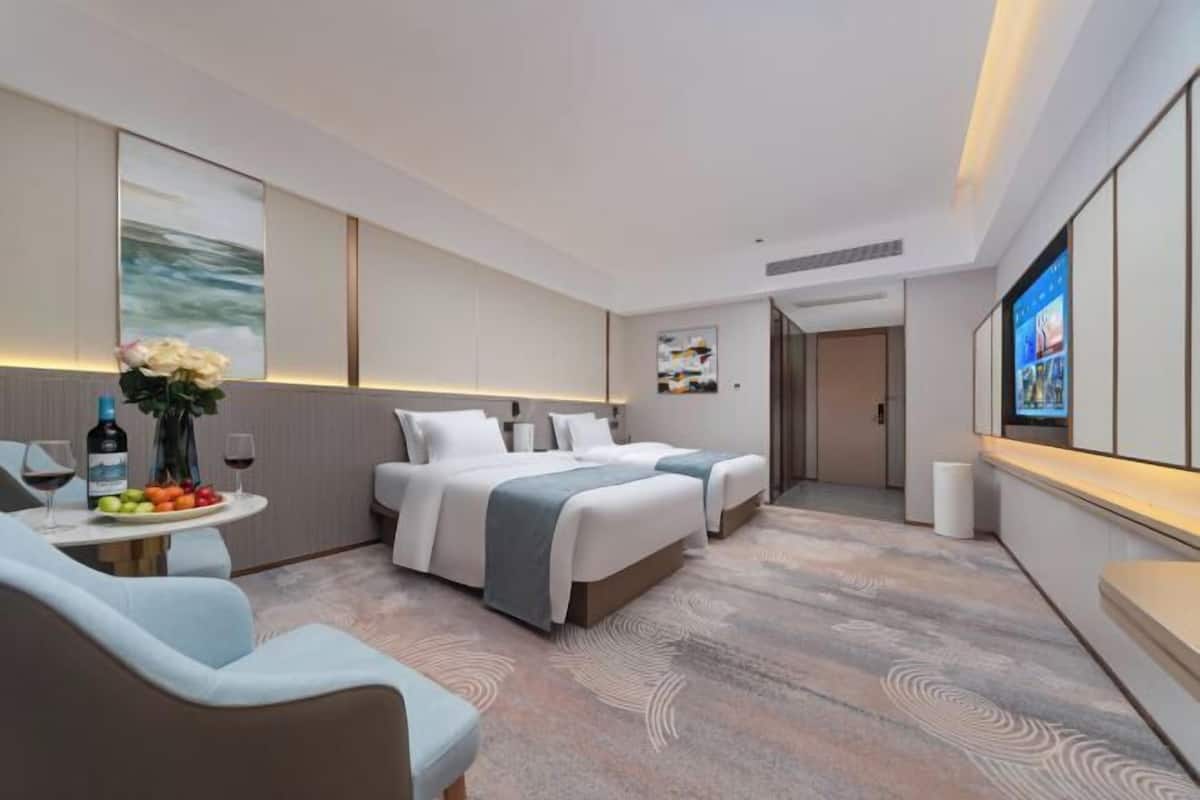 Une chambre d’hôtel moderne dotée d’un grand lit, d’un coin salon avec une table et d’un téléviseur fixé au mur.