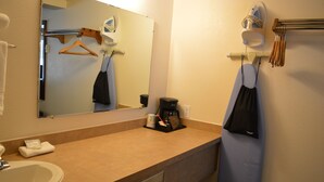 Une salle de bain équipée d’un lavabo, d’un miroir, d’un porte-serviettes et d’une serviette accrochée au mur.