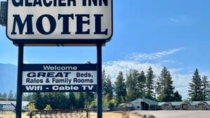 Une enseigne du Glacier Inn Motel faisant la publicité de ses excellents lits, de ses tarifs avantageux, de ses chambres familiales et de ses équipements, tels que le Wi-Fi et la télévision par câble.