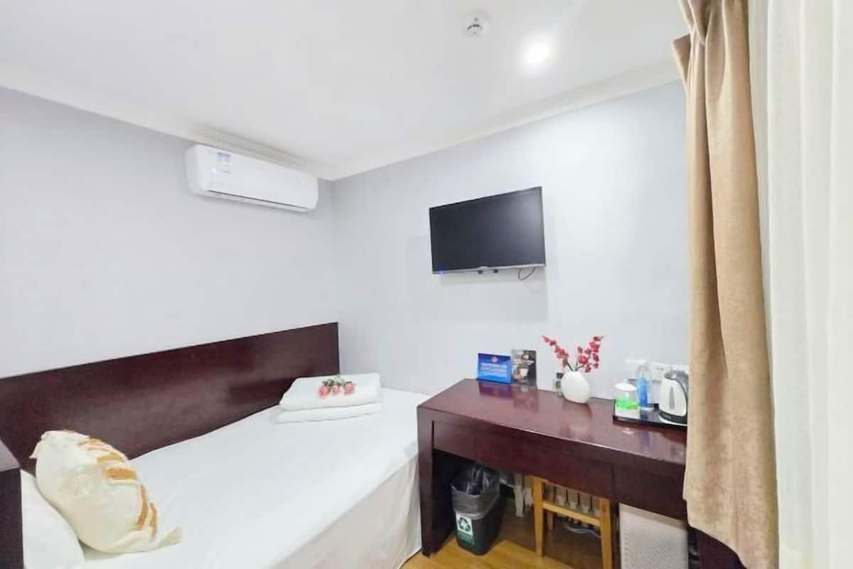 Une chambre d’hôtel équipée d’un lit, d’un bureau, d’une télévision et d’un appareil de climatisation.