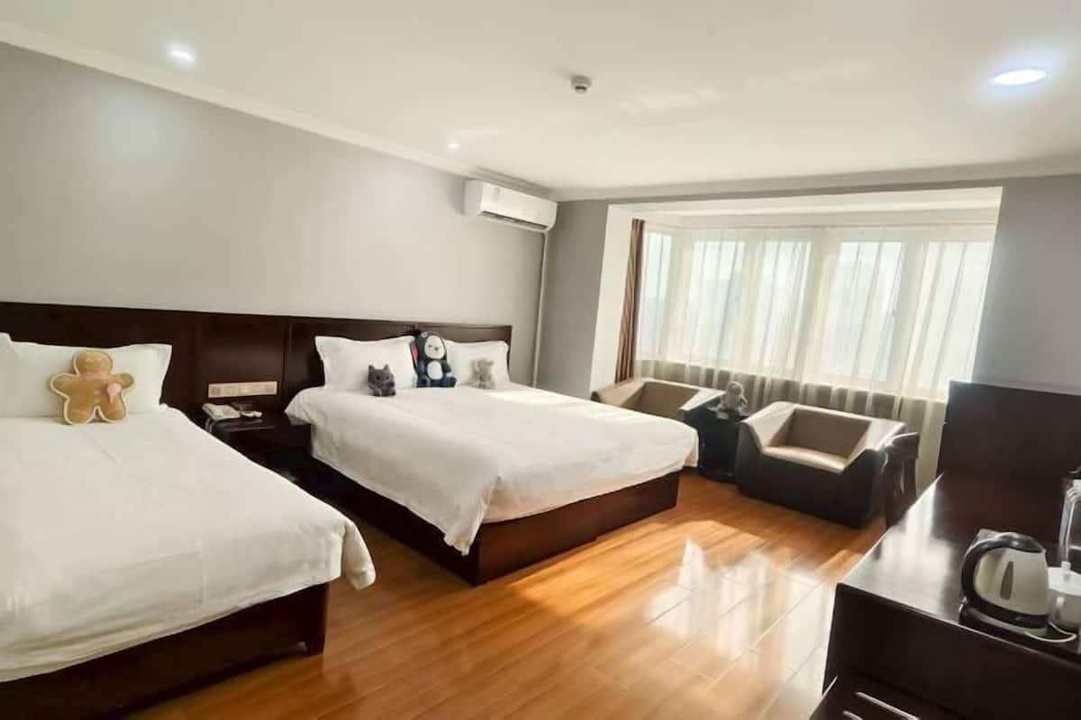 Une chambre d’hôtel avec deux lits, un canapé, un bureau et une fenêtre avec des rideaux.