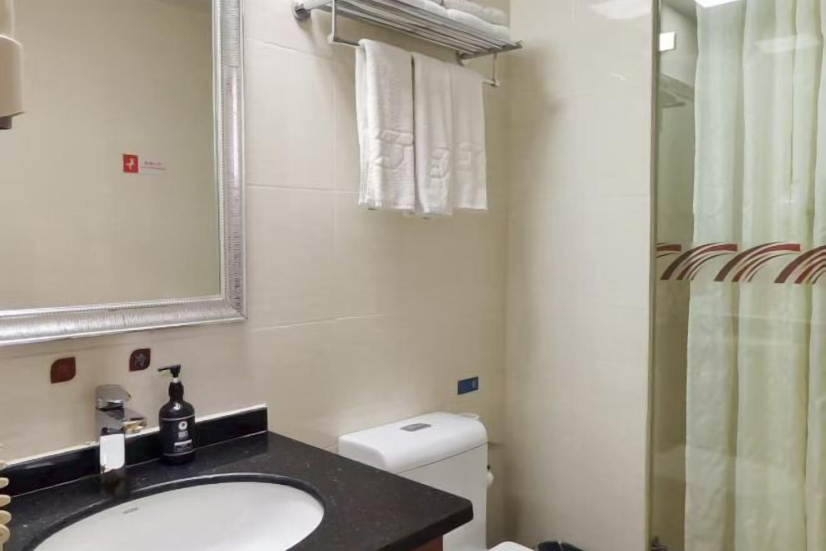 Un baño con lavamanos, espejo, toallero y cortina de ducha.