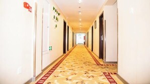 A hotel hallway with a patterned carpet, doors on both sides, and a bright ceiling. - Jintai Home (Beijing North Railway Station Jiaotong University Branch) (Beijing)