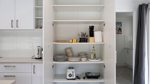 A kitchen with white cabinets, a toaster, a kettle, and a shelf with kitchen utensils. - Wolaroi Villa 2, with Netflix and Disney Plus - In a Quiet Street (Orange)
