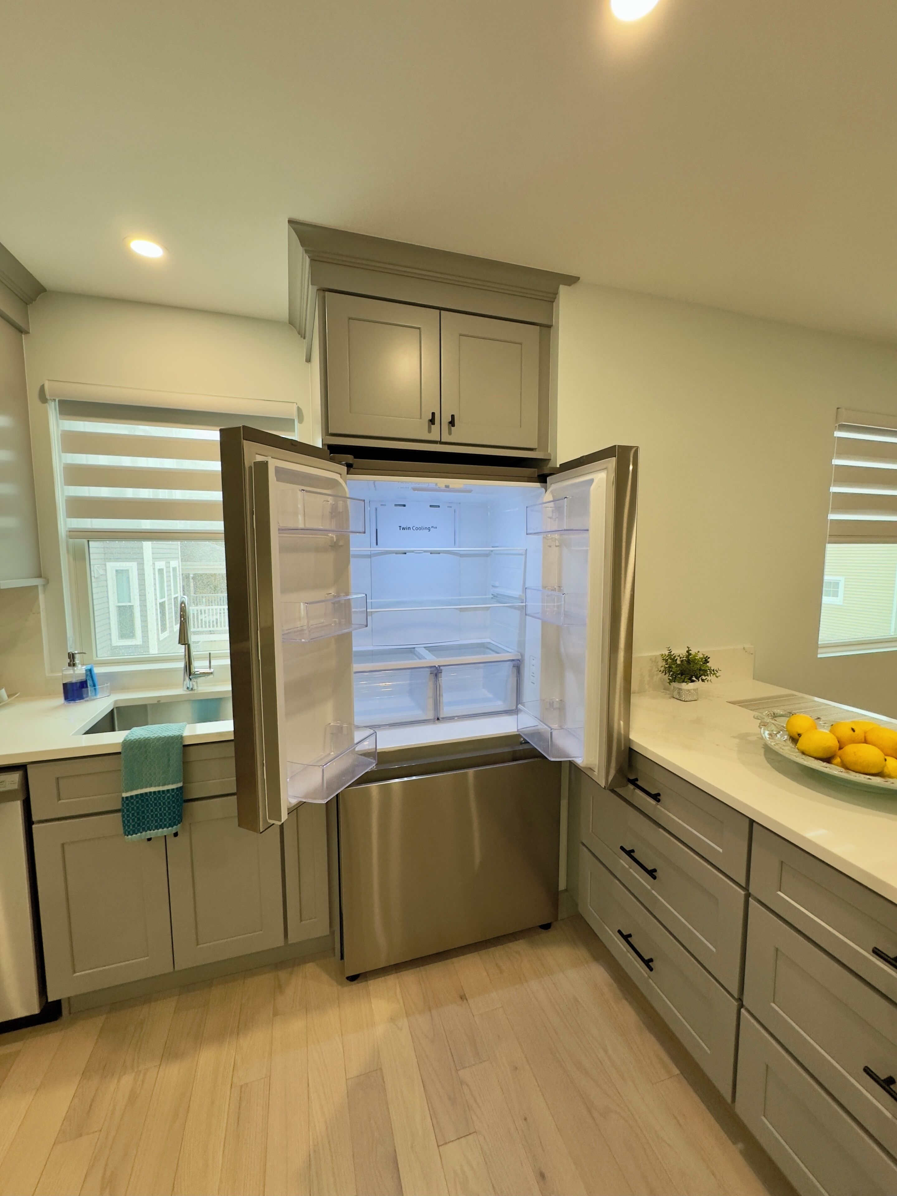 Una cocina moderna con un refrigerador de acero inoxidable, un fregadero y una encimera con un bol de limones.