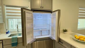 Una cocina moderna con un refrigerador de acero inoxidable, un fregadero y una encimera con un bol de limones.