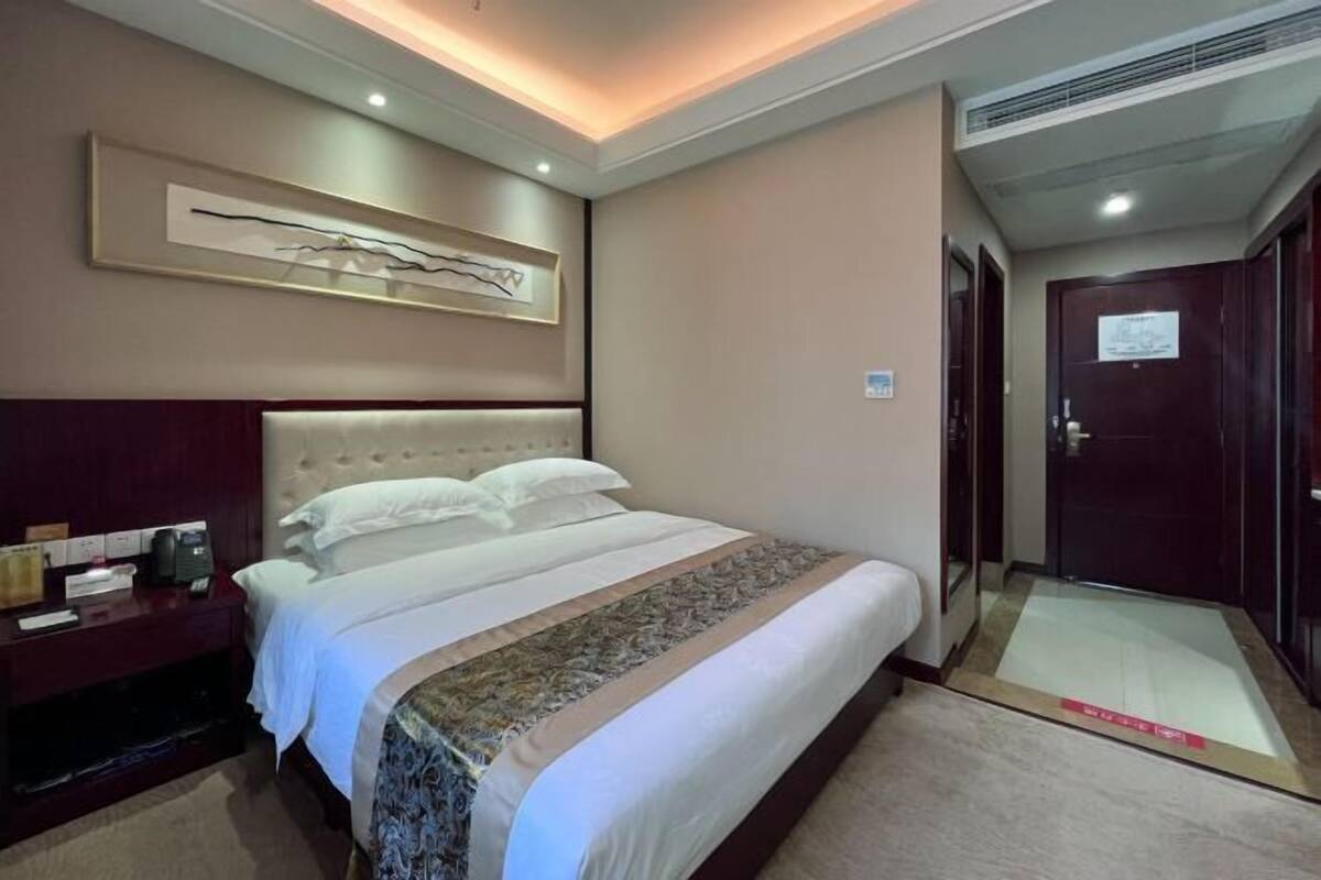 Una habitación de hotel con cama, mesita de noche, una obra de arte en la pared y una puerta.
