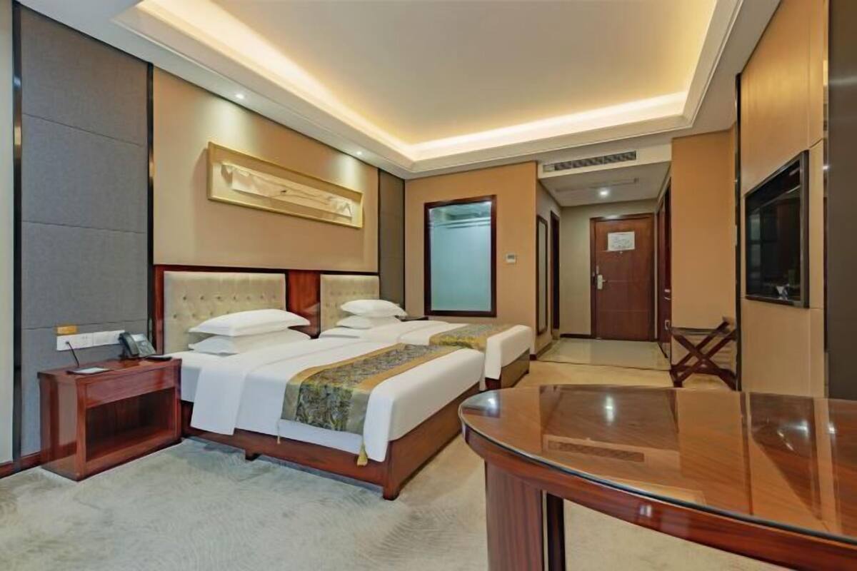 Una habitación de hotel con una cama grande, mesitas de noche, un escritorio y un televisor.