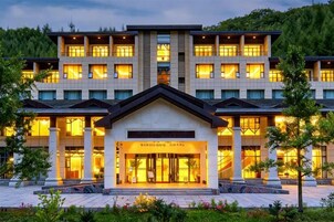 A multi-story hotel with a central entrance, large windows, and a landscaped front garden.