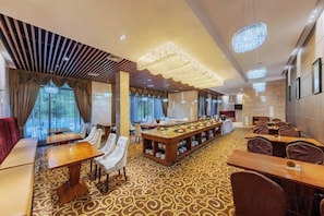 A hotel dining area with long tables, chairs, and a bar.