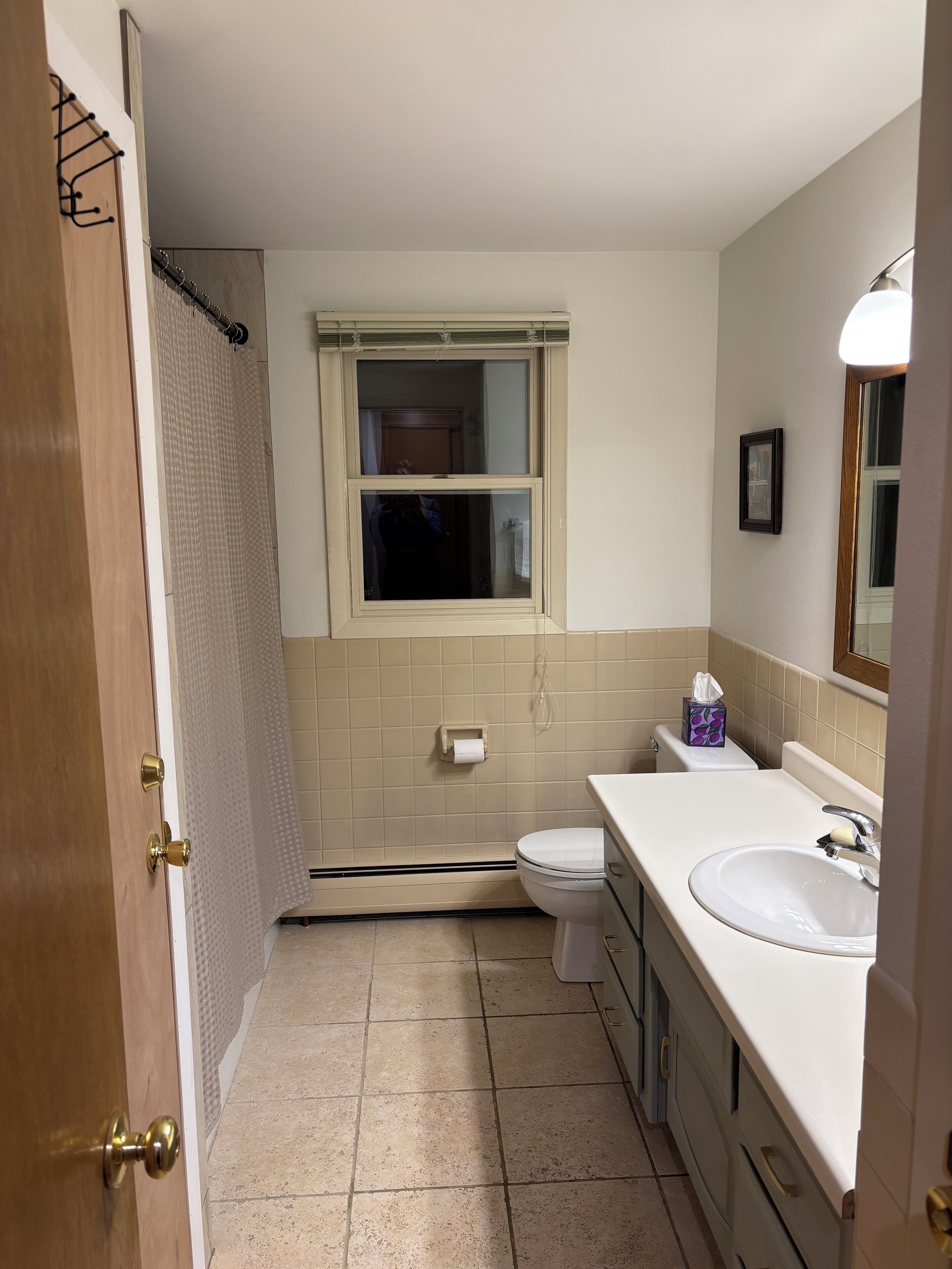 A bathroom with a toilet, sink, and window.