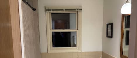 A bathroom with a toilet, sink, and window.