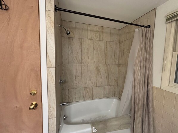 A bathroom with a bathtub, shower, and a curtain. - Gary's Game-Day Getaway only 1.4 miles from Lambeau! (Green Bay)
