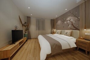 A modern bedroom with a large bed, wooden flooring, a TV on a stand, and a wall mural.