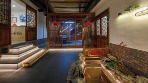 Een traditionele Chinese entree met houten deuren, een pad van stenen en een klein waterpartij.