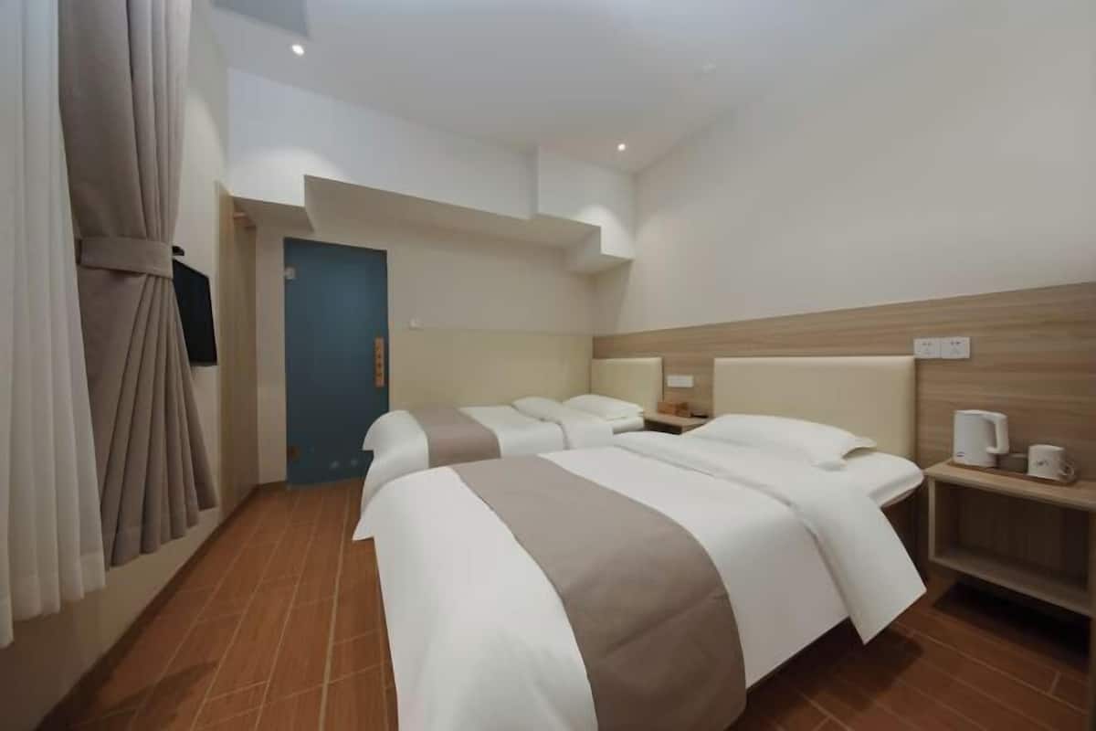 A hotel room with two beds, a TV, a coffee machine, and a wooden headboard.