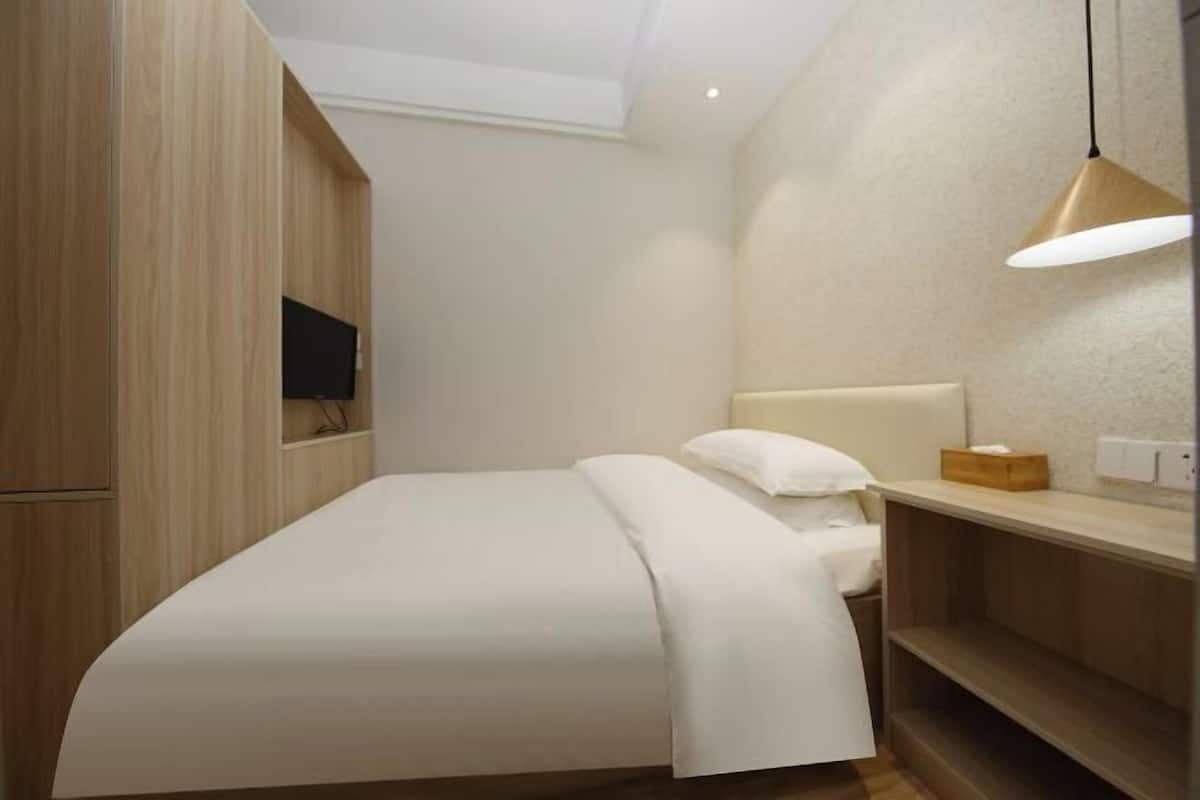 A modern bedroom with a bed, a bedside table, a lamp, and a TV mounted on the wall.