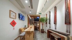 Een klassiek interieur met een houten receptiebalie, een zithoek en decoratieve elementen zoals kalligrafie en traditionele objecten.