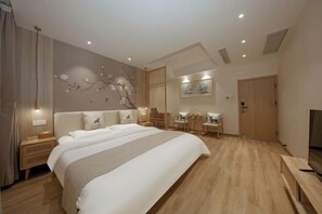 A modern hotel room with a large bed, bedside tables, a desk with chairs, a television, and a bathroom with a mirror and sink. - Yishe Inn (Yangzhou Slender West Lake Branch) (Yangzhou)