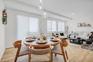 Un comedor con una mesa redonda de madera, sillas y una lámpara colgante.