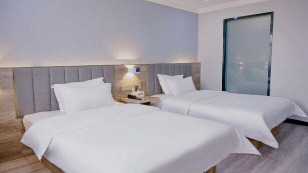 A hotel room with two beds, a nightstand with a lamp, and a sliding door. - 7 Days Premium (Zibo Zichuan Hongtai) (Zibo)