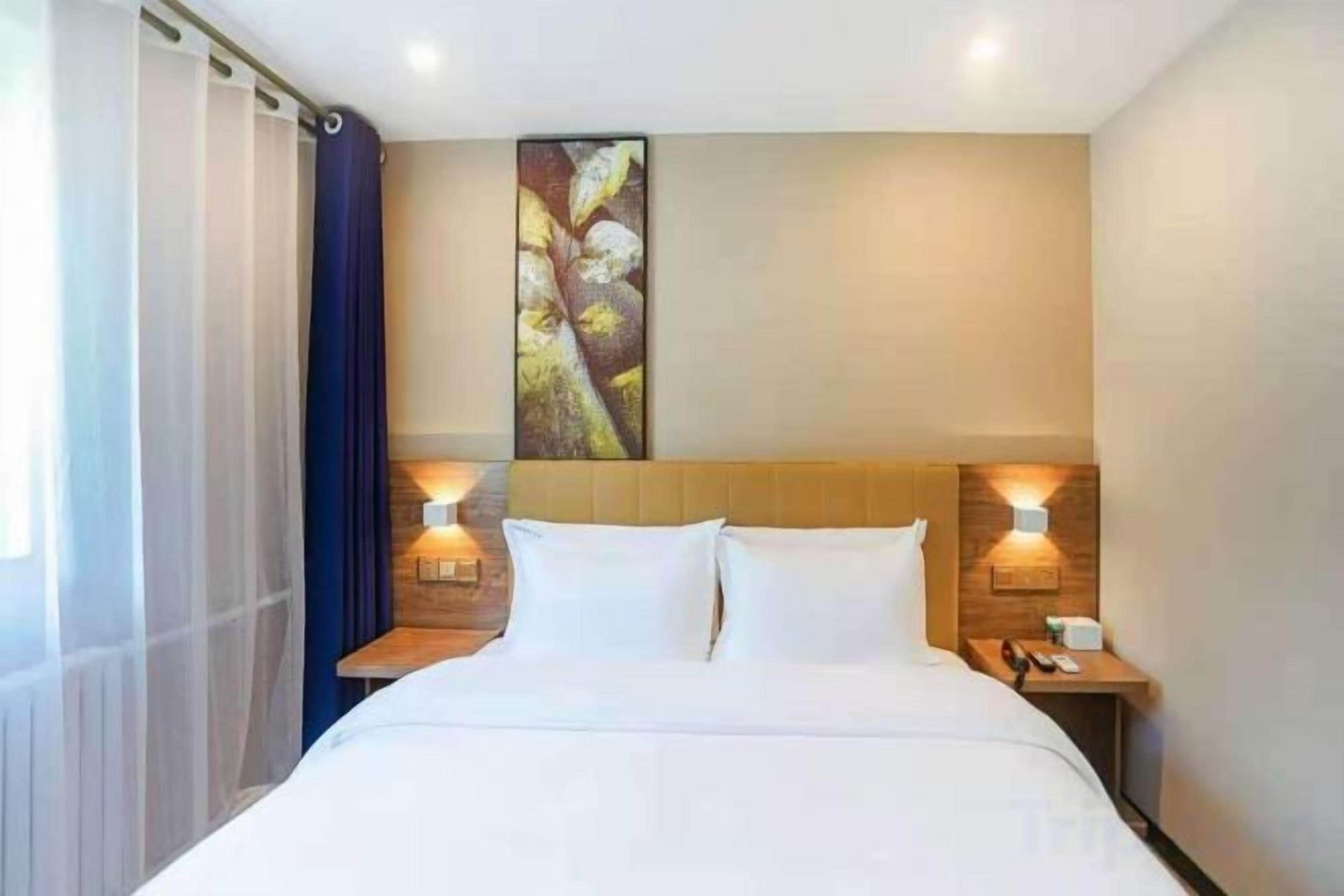 Habitación de hotel con una cama grande, dos mesitas de noche con lámparas, una obra de arte en la pared y una ventana con cortinas.